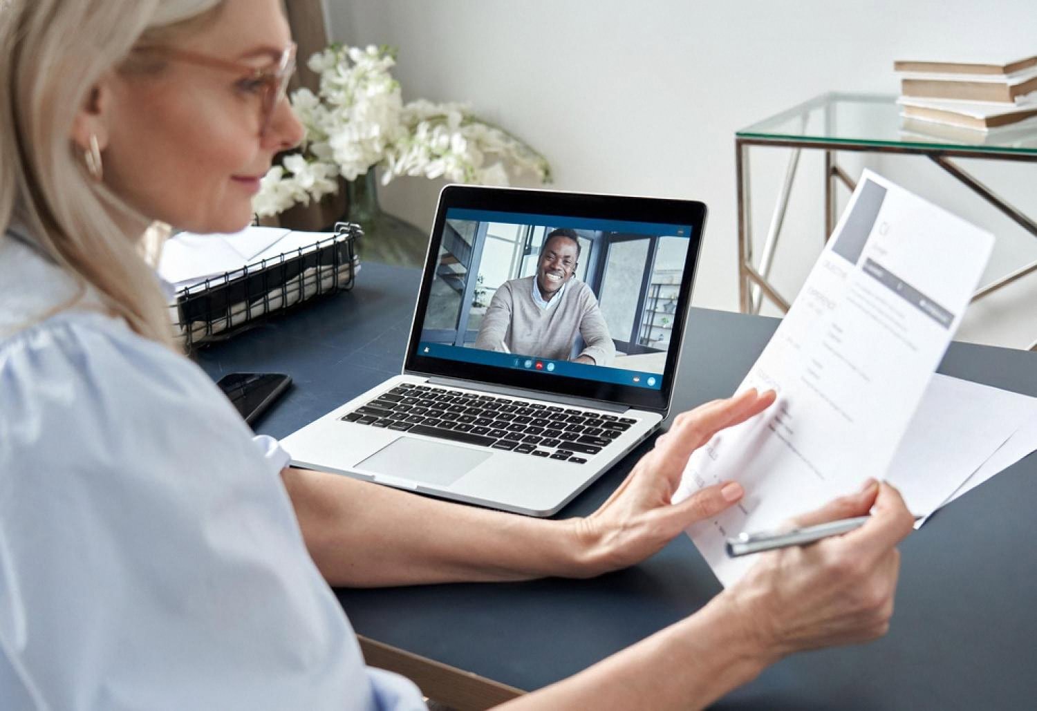 HR specialist on a video call reviewing a candidate's CV from home