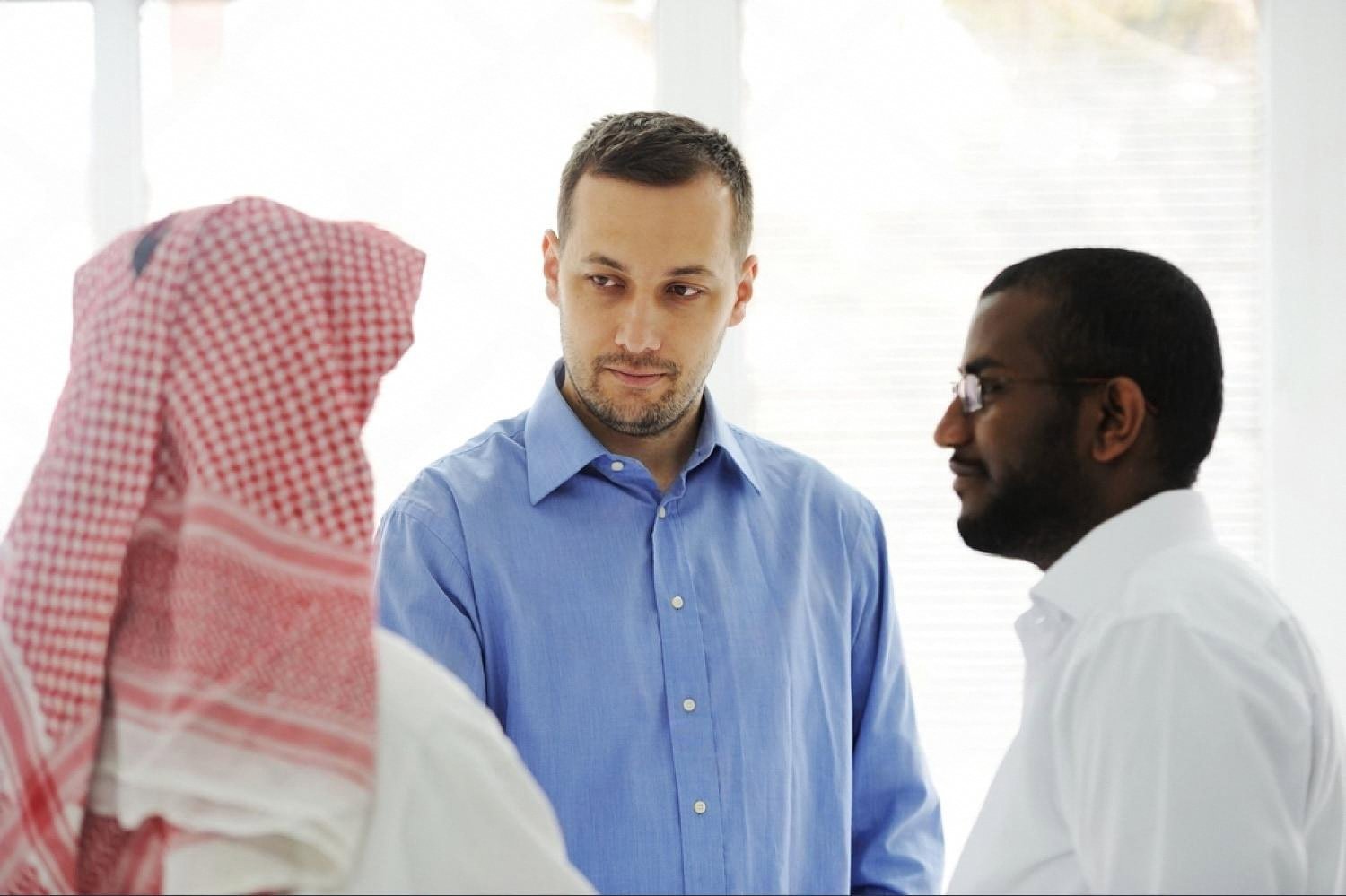 Foreign investor in discussion with Middle Eastern business partners in a meeting room